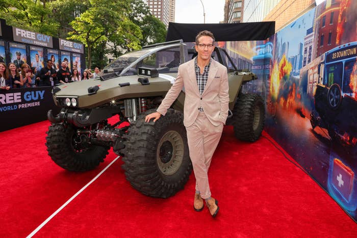 Ryan Reynolds attends the World Premiere of 20th Century Studios&#x27; Free Guy and stands in front of a large vehicle