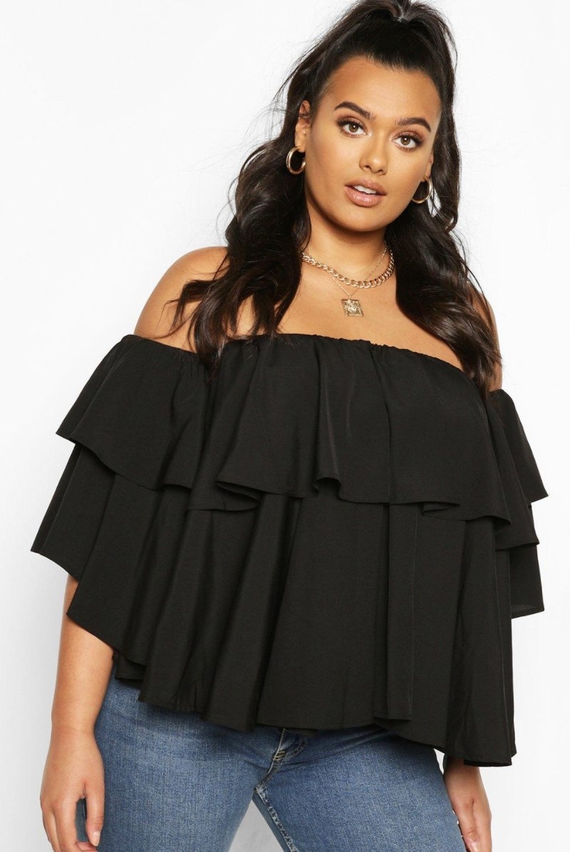 a model wearing an off the shoulder peplum top in black