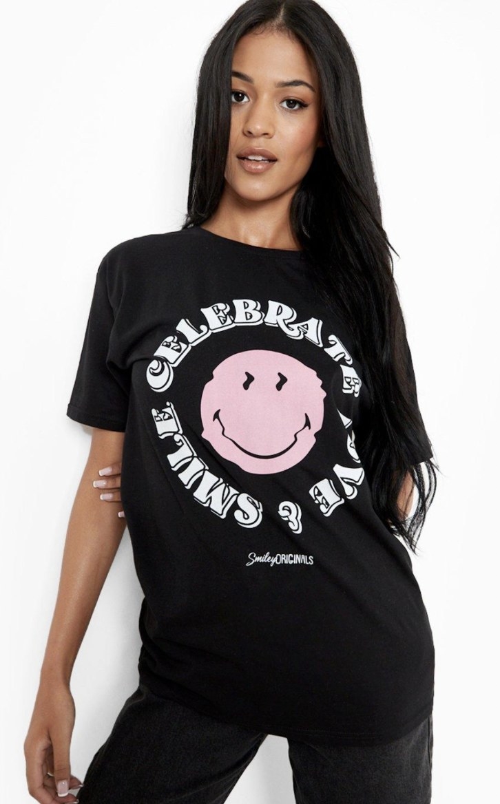 a model wearing a black t-shirt with a pink smiley face on the front
