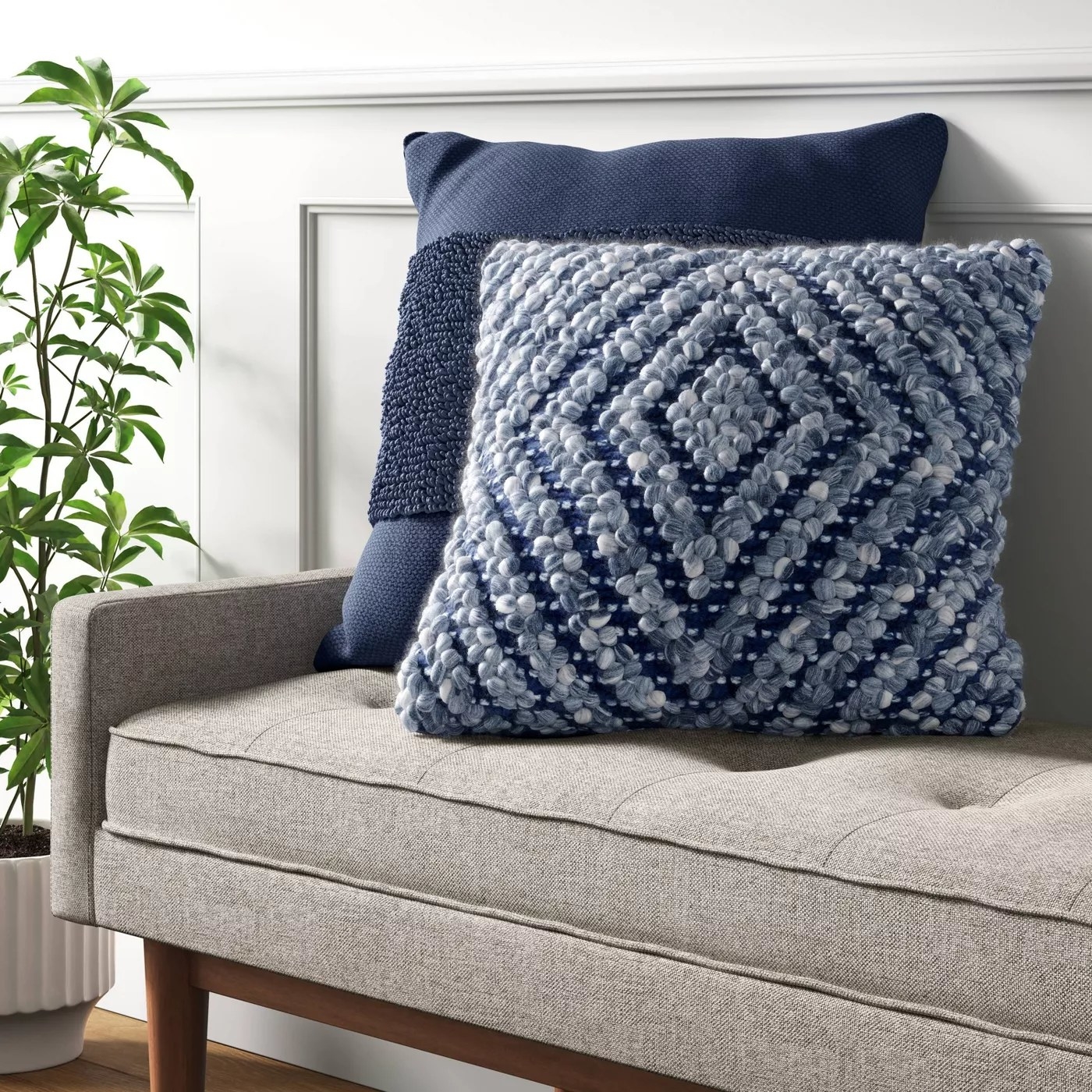 The blue throw pillow with a diamond pattern on a bench