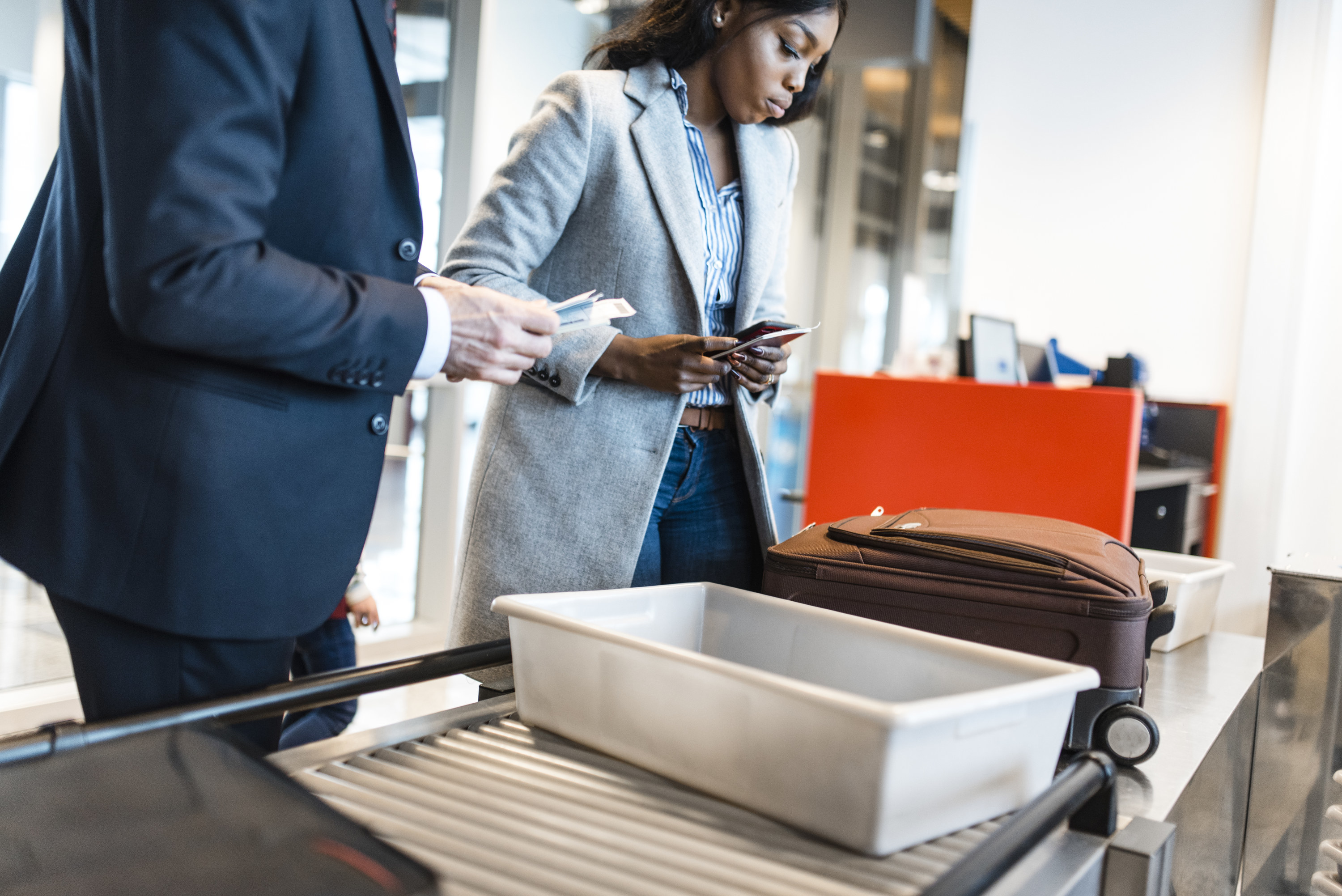 Two people putting their items in bins for airport security