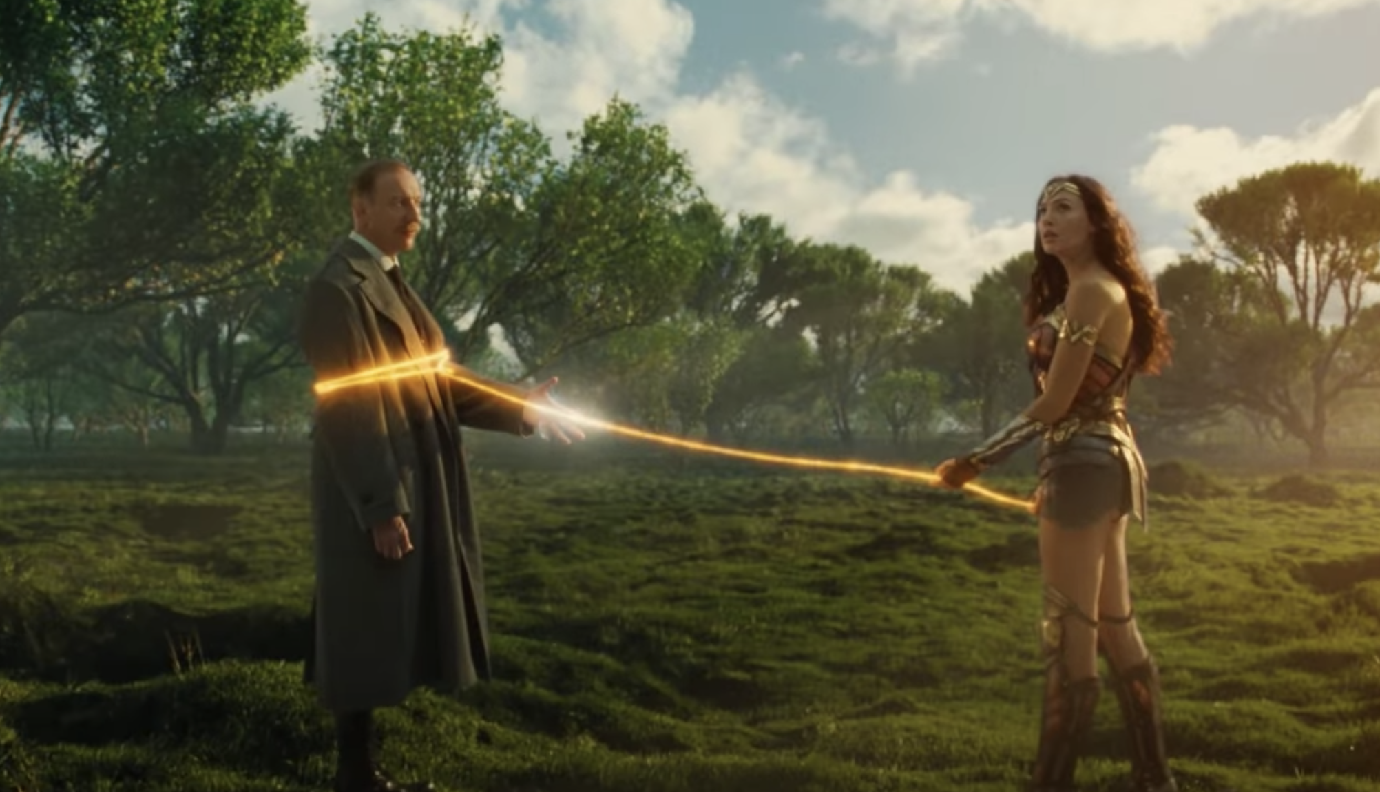 Wonder Woman with her lasso around Ares in a field