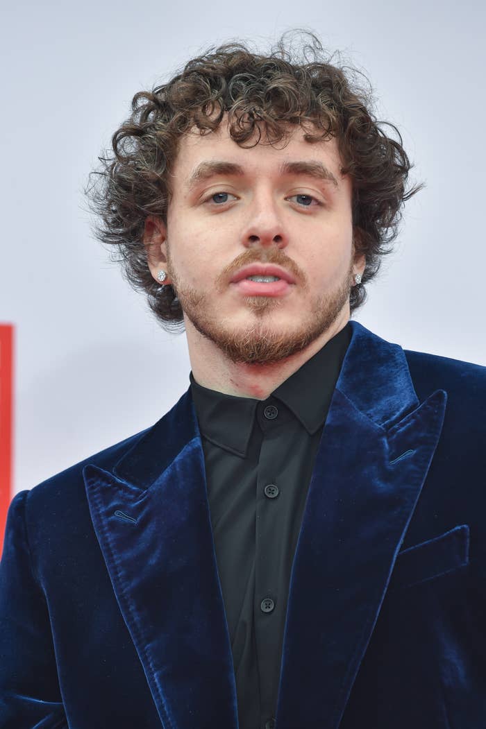 Jack Harlow poses on the red carpet while wearing a jacket and button-down shirt
