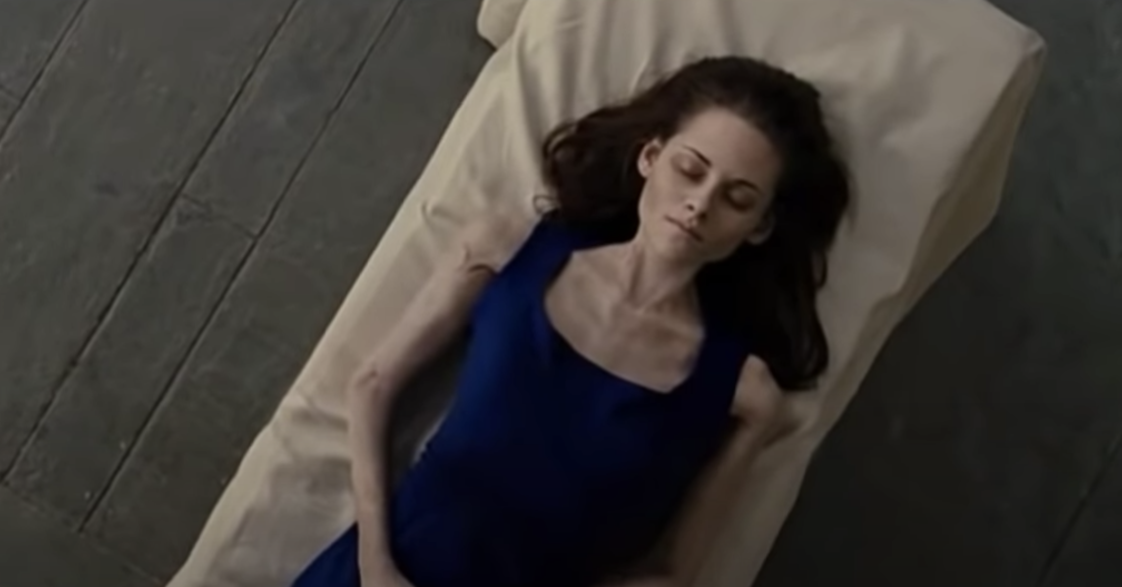 Bella lying lifeless on a bed