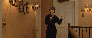 A GIF of Emily Blunt playing Mary Poppins catching an bag and umbrella out of thin air
