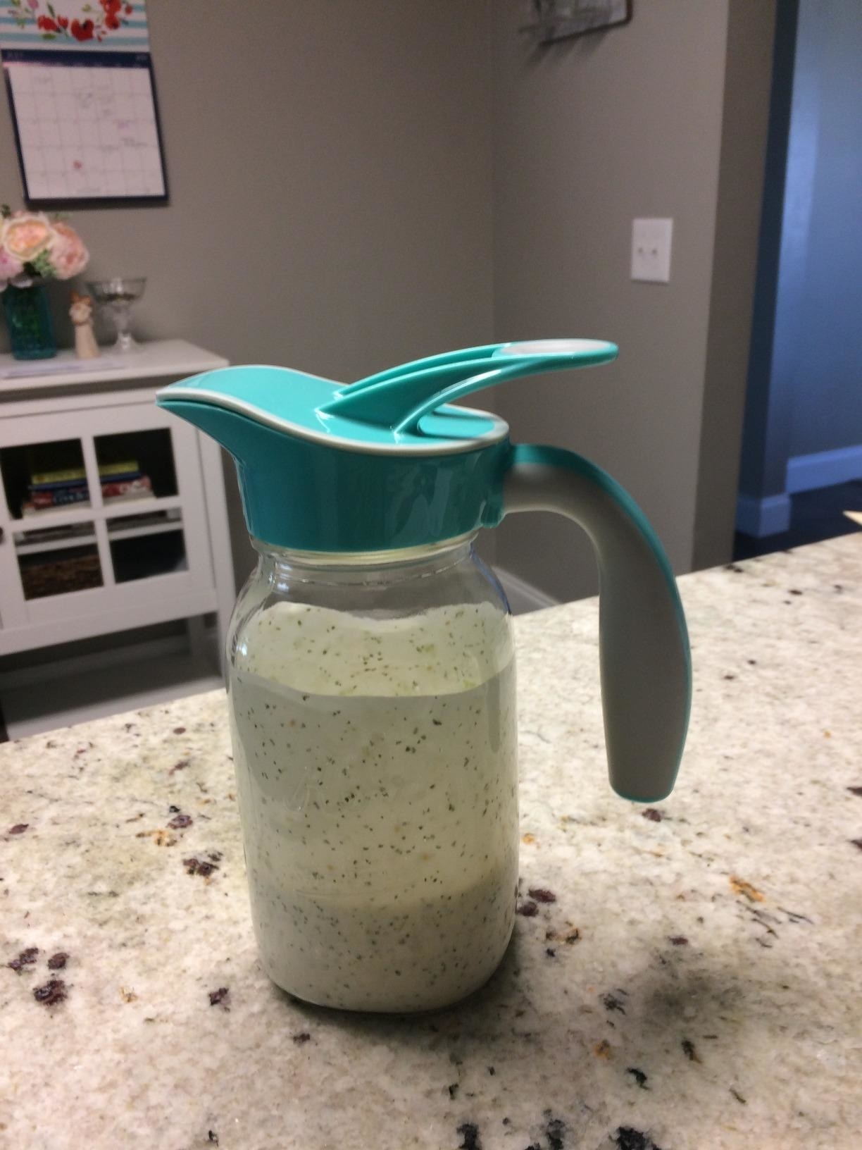 reviewer image of the blue ergo spout on a mason jar full of salad dressing