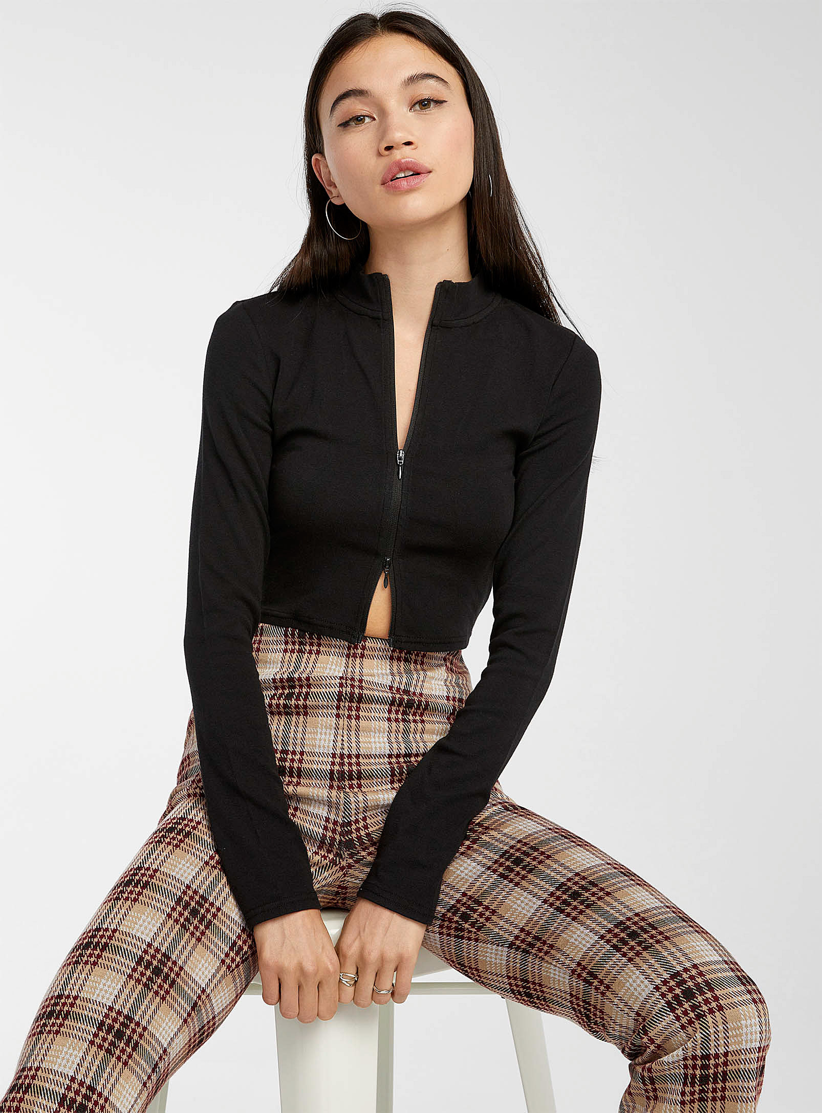 a person sitting on a stool wearing the sweater with checkered pants
