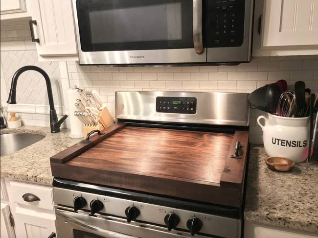 stove with a dark wood stovetop cover with handles on top of it
