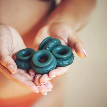 Model holding four dark green silicone rings in hands