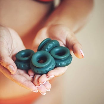 Model holding four dark green silicone rings in hands