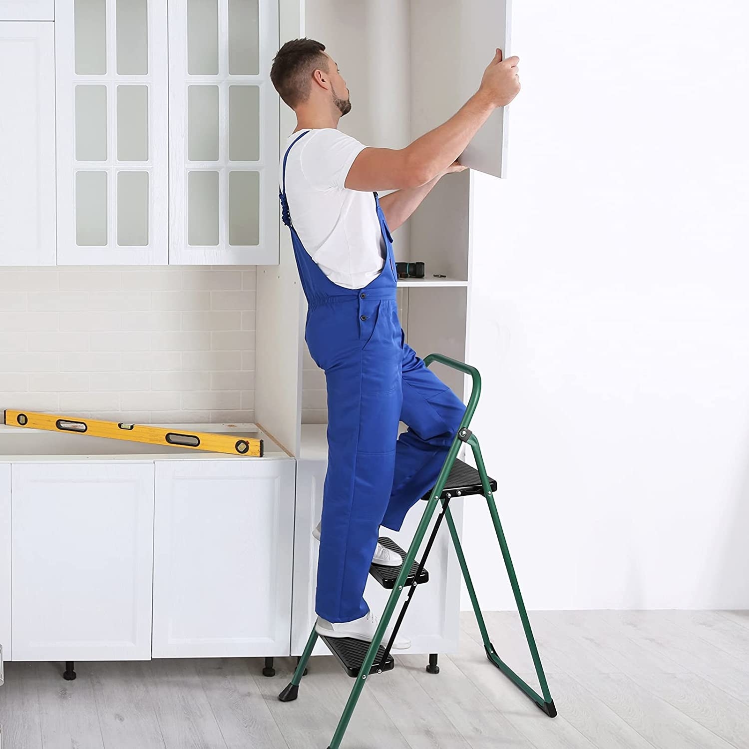 a model steps on the step ladder to install a cabinet door in a kitchen