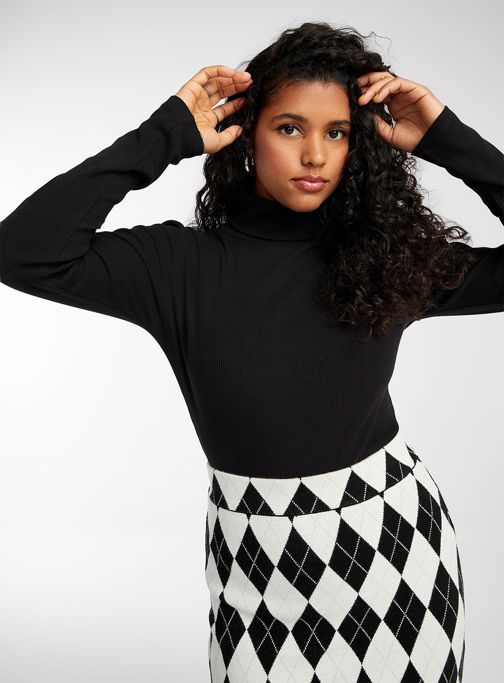 a person wearing the turtleneck with a patterned skirt