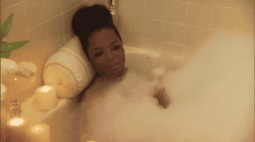 Oprah in a bubble bath with a glass of wine