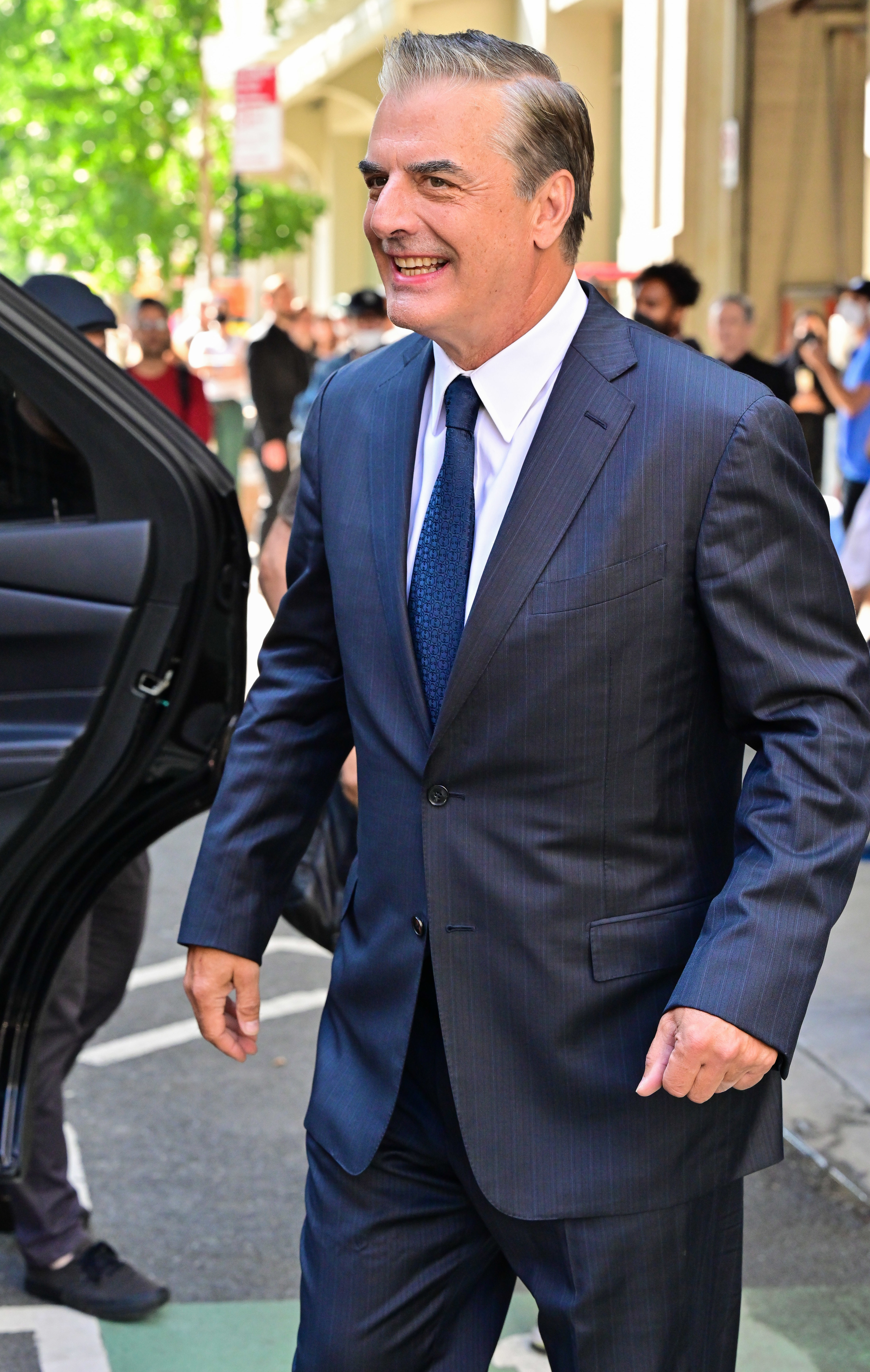 Chris Noth is pictured smiling on the set of And Just Like That...