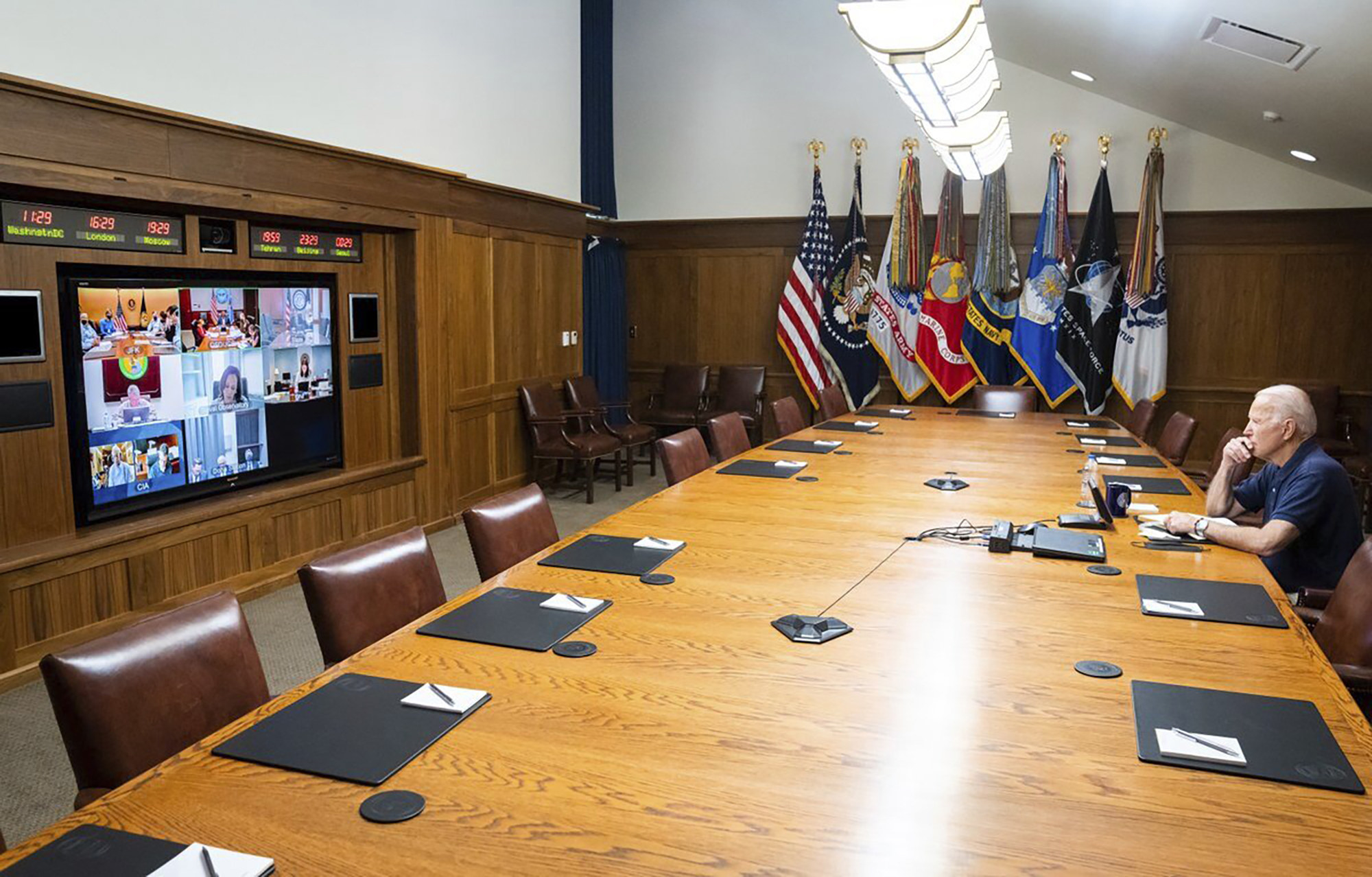 President Joe Biden sitting alone at a table at Camp David as he virtually met with his national security team and senior officials for a briefing on Afghanistan
