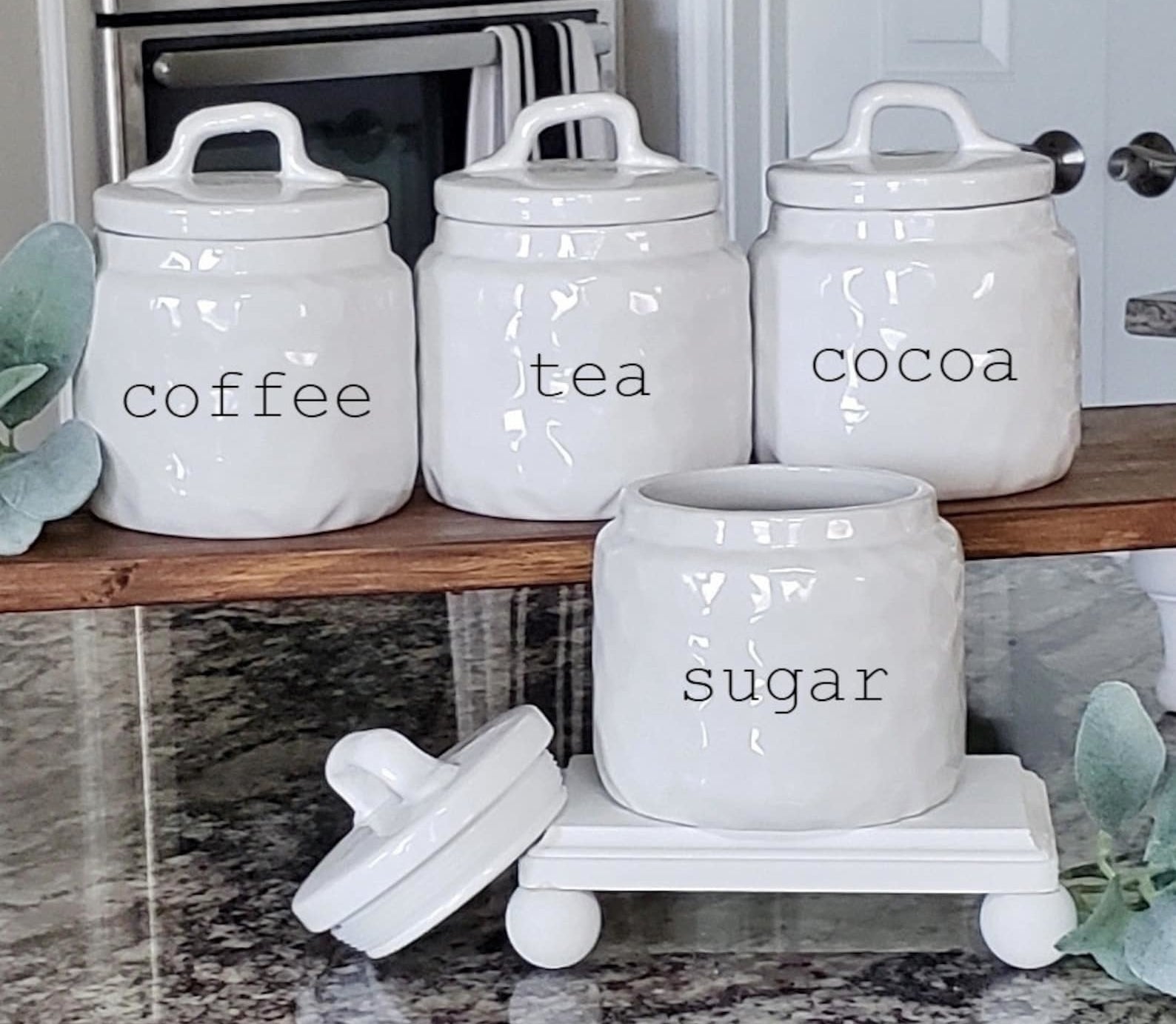 four white canisters labeled for coffee tea cocoa and sugar