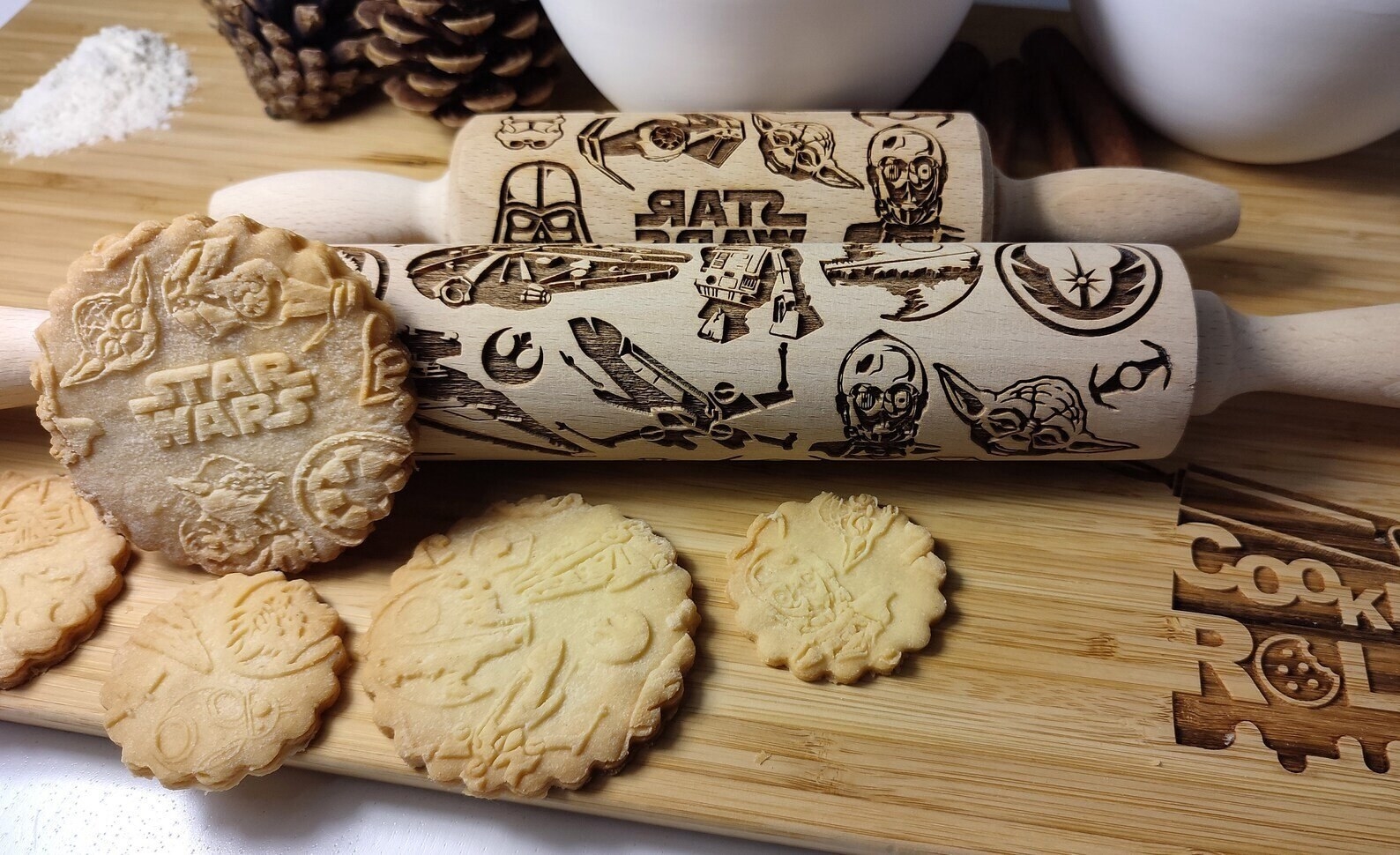 two rolling pins beside several baked sugar cookies with imprints from the pins