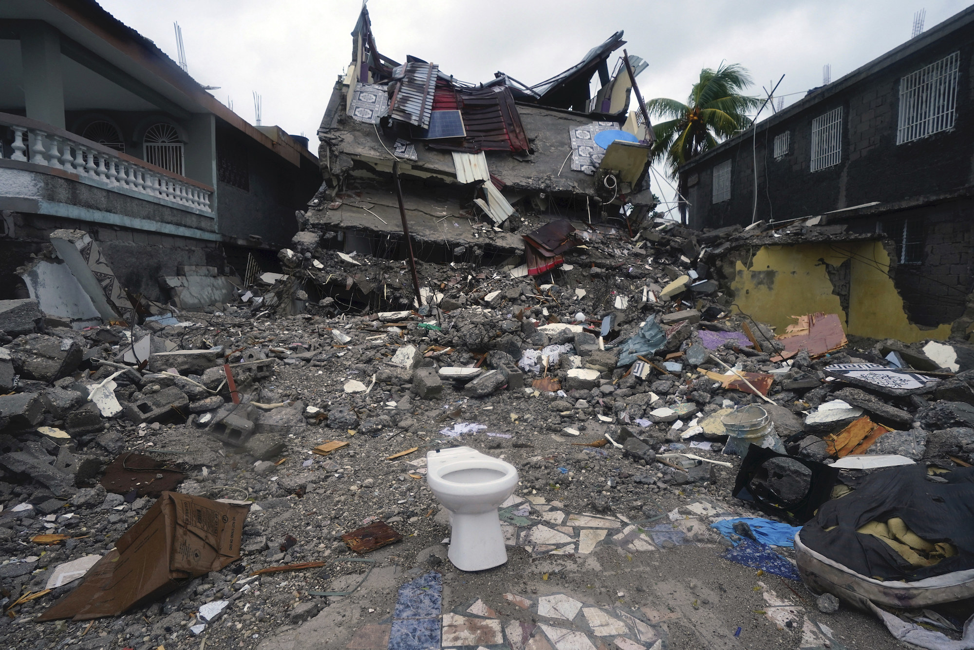 A multistory building collapsed into a pile of rubble amid debris from homes scattered all over the street