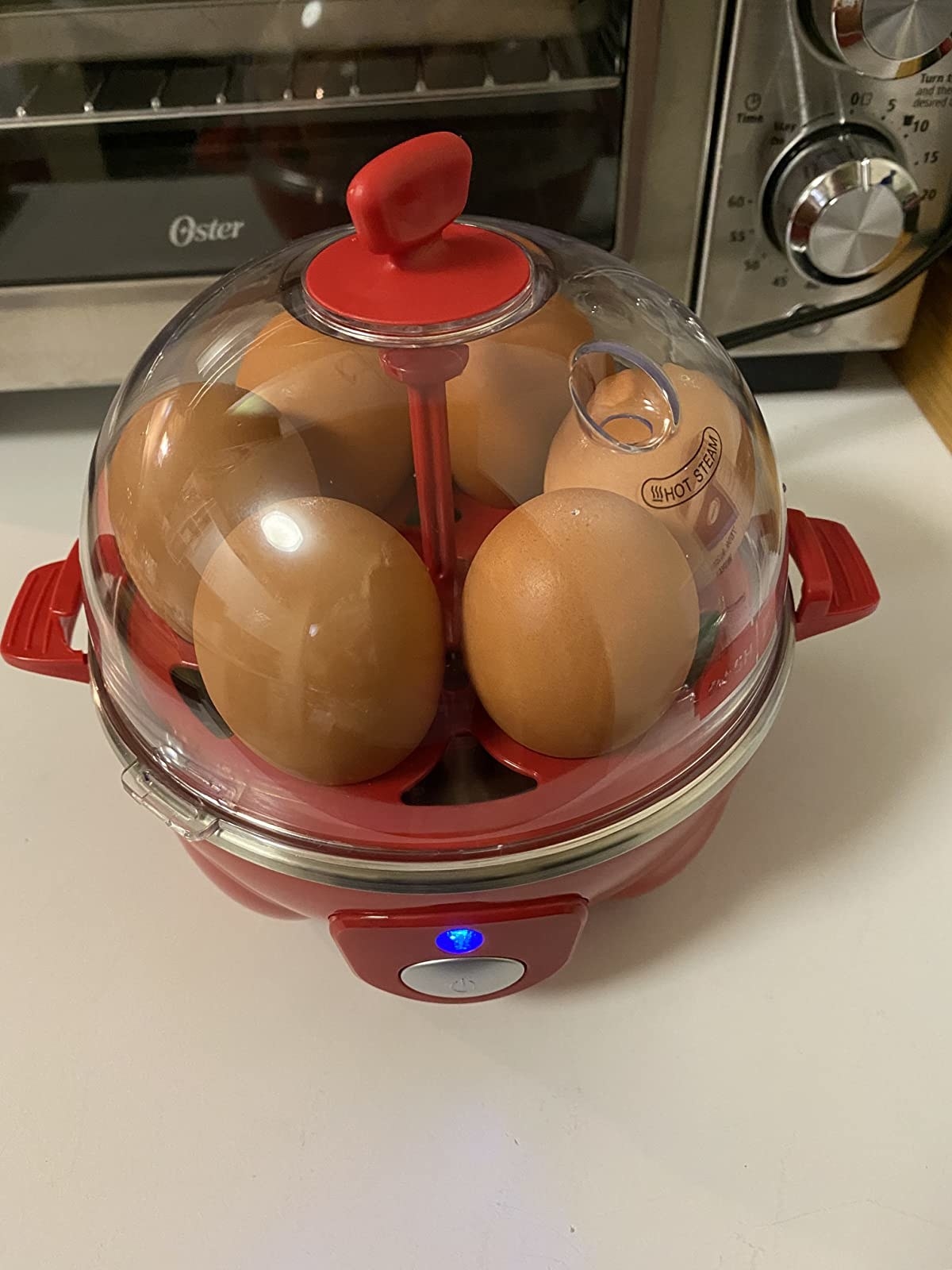 reviewer image of six brown eggs in a red electric egg cooker