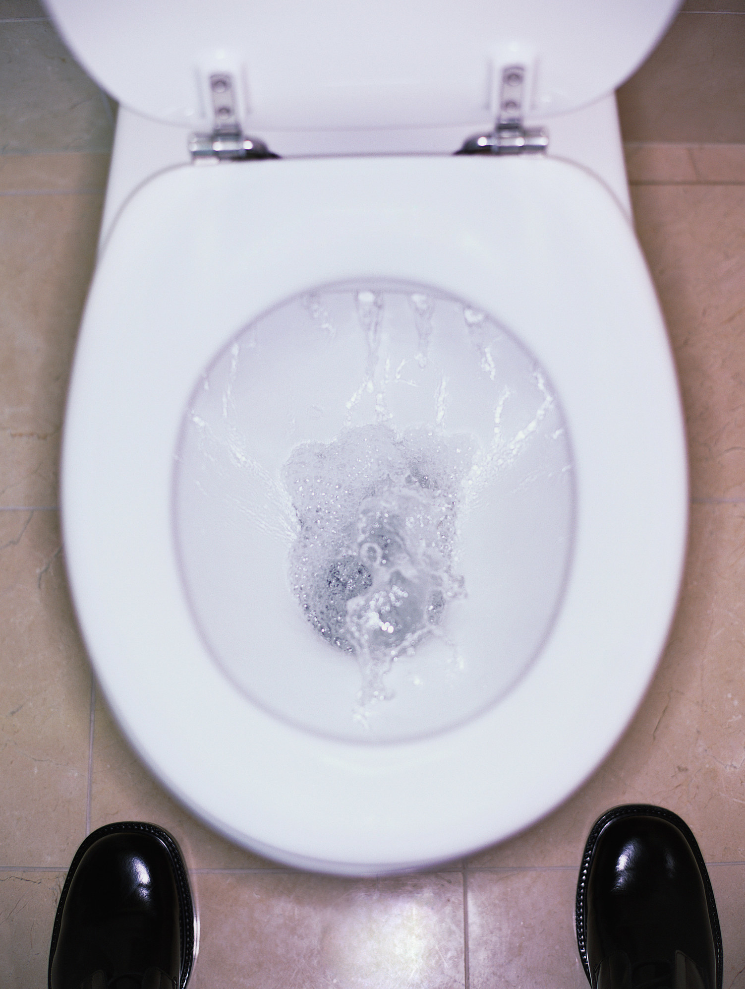 A man standing over a public toilet.