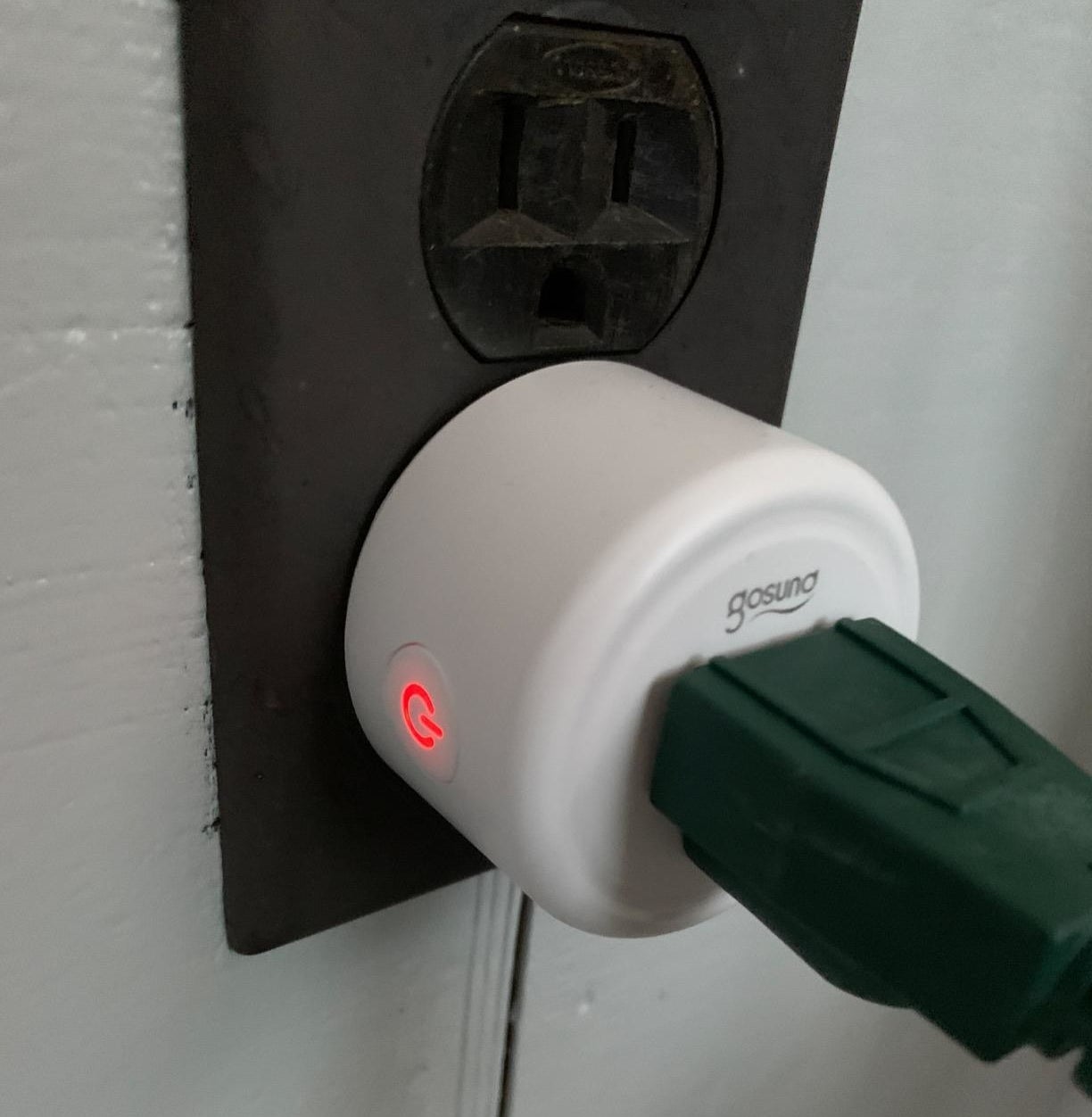 a reviewer photo of a smart outlet plugged into a wall socket