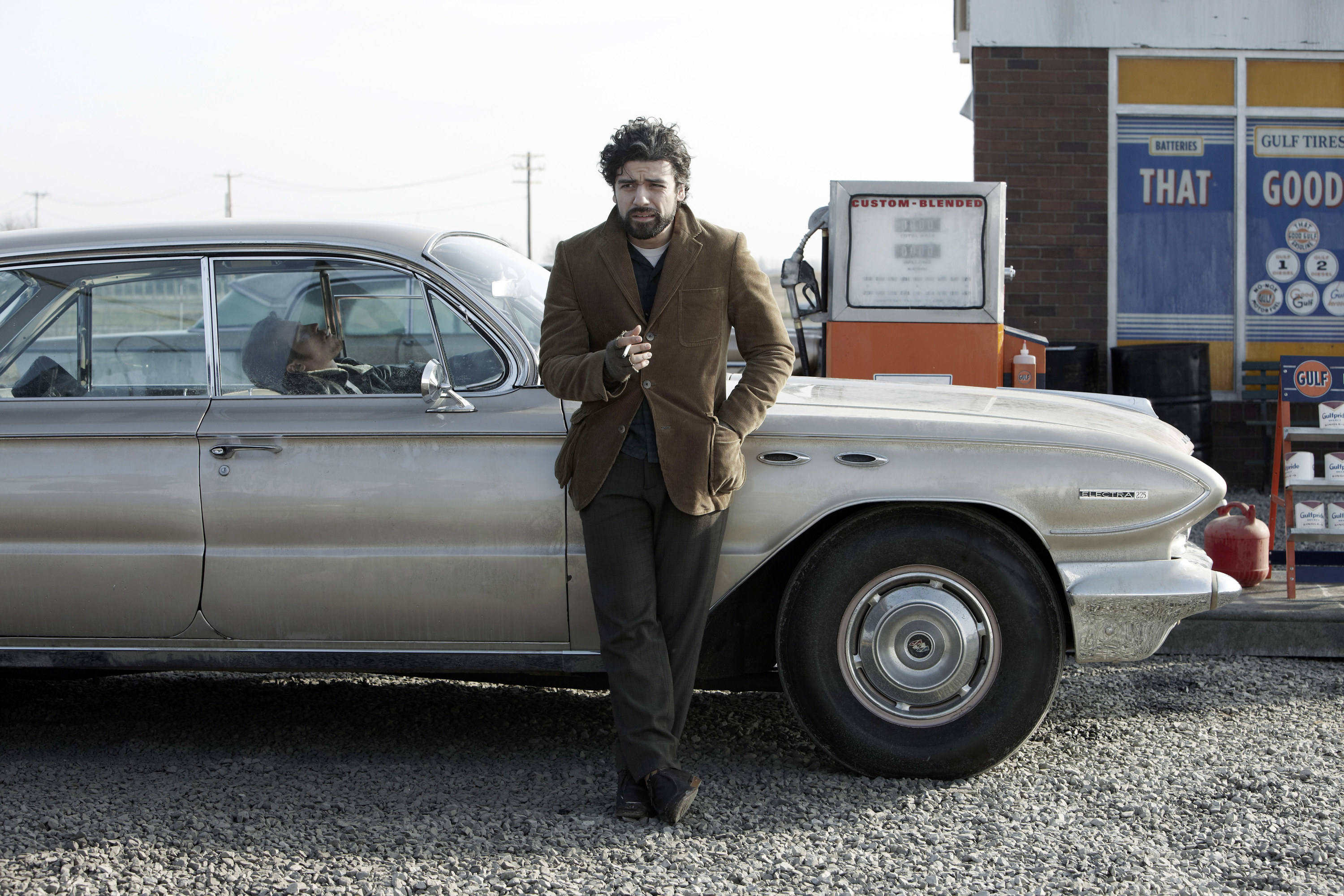 Llewyn standing in front of his car at the gas station