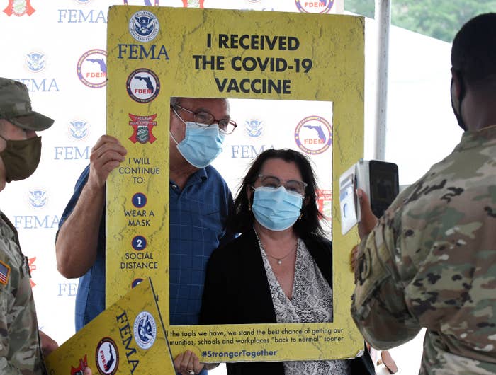 Two people holding a frame that says &quot;I received the COVID-19 vaccine&quot;