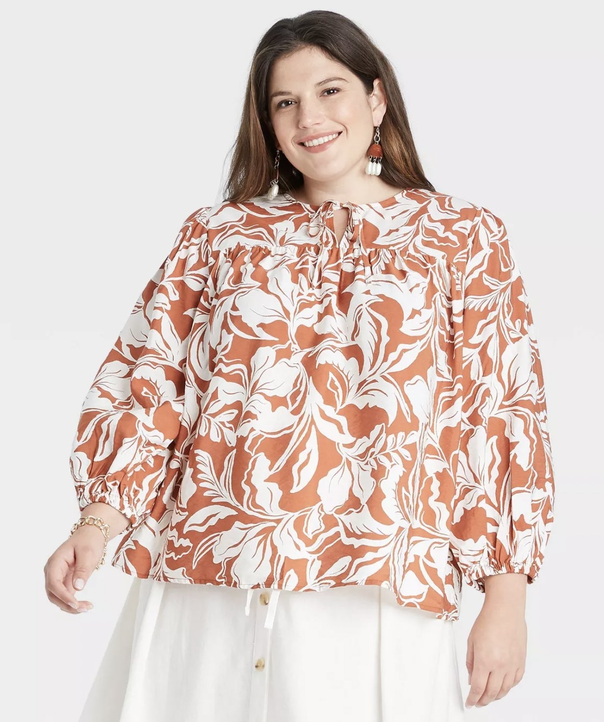 model wearing the blouse in a orange and white floral design