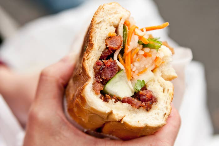 Someone holding a banh mi sandwich.