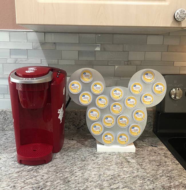 a silver mickey-shaped k-cup holder next to a keurig machine