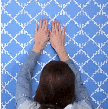 person smoothing out a wallpaper and cutting with utility knife