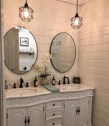 Reviewer image of two of the caged pendant lights hung above two bathroom sinks 