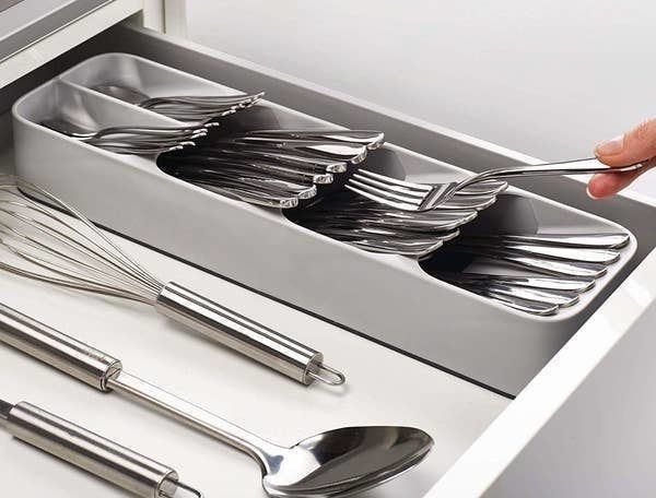 person putting a fork into the gray cutlery organizer