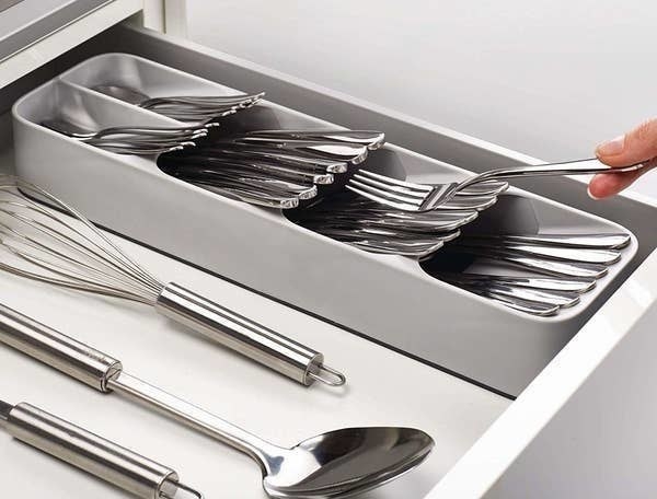 person putting a fork into the gray cutlery organizer