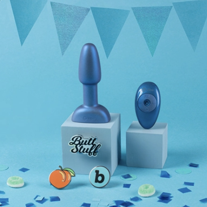 Metallic blue butt plug and wireless remote next to logo pin buttons