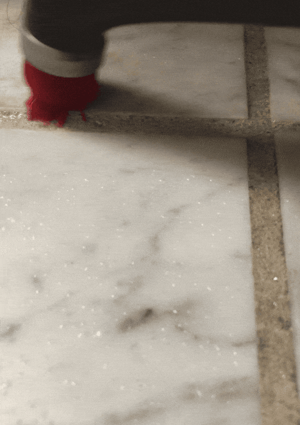 Gif of BuzzFeed Shopping reviewer cleaning grout with the brush 