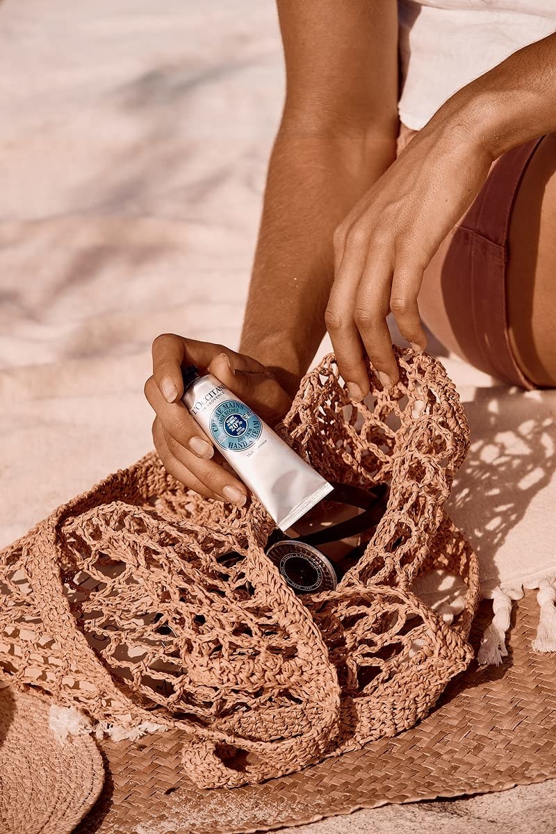 A person putting the hand lotion into their beach bag