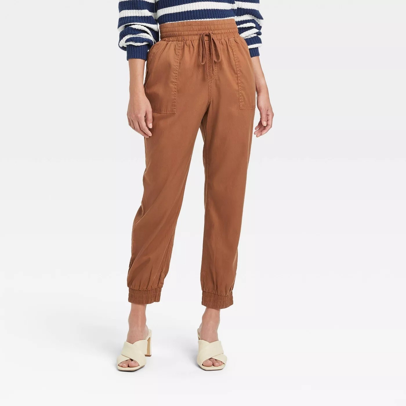 Model wearing brown pants with side pockets and tie string detail around waist