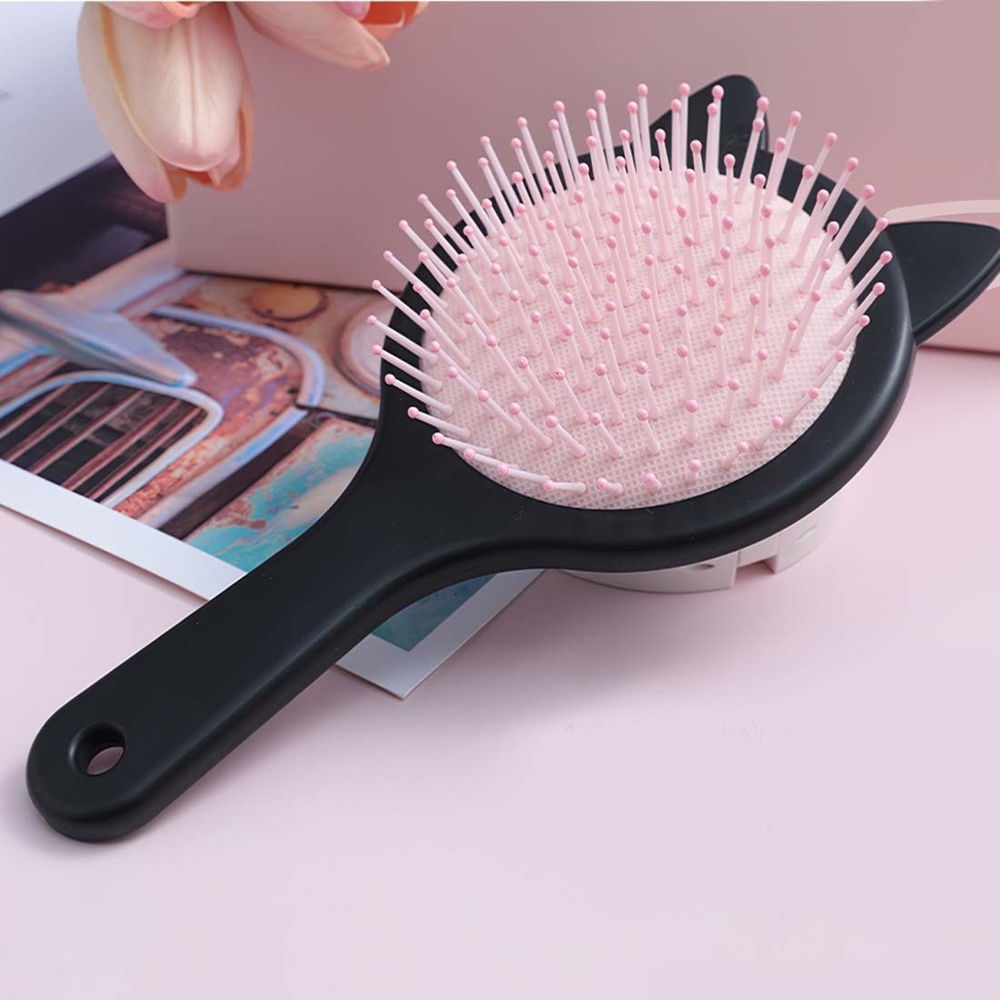 A pink detangling hair brush with a black handle and cat ears