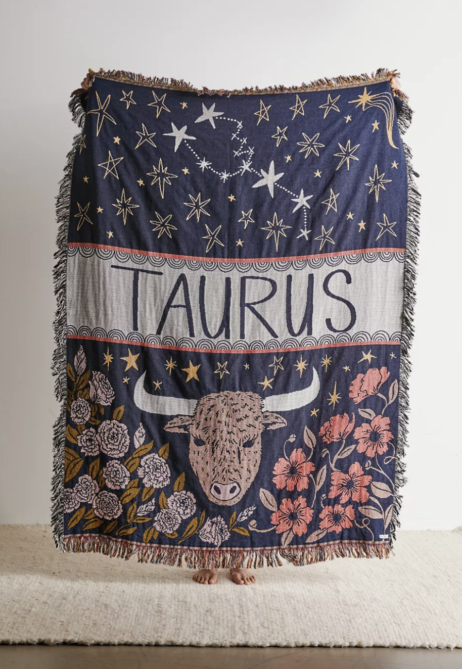 a fringed throw blanket with a taurus-inspired design on it and florals
