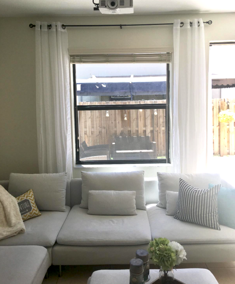 view of light gray sectional couch in front of window with sheer white curtains