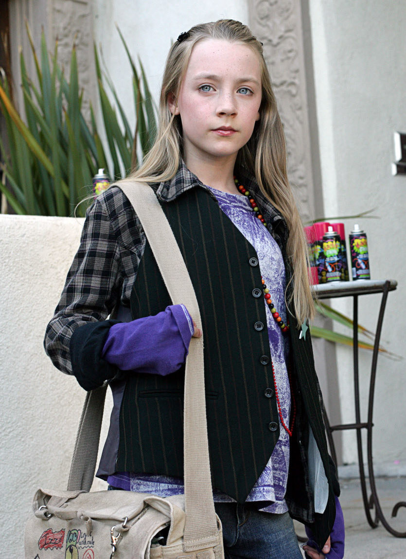 A very young Saoirse Ronan carrying a messenger backpack with long hair