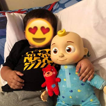 Reviewer's child holding the Cocomelon doll in bed