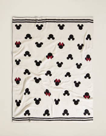 a cream colored blanket with black icons of mickey and minnie heads on them
