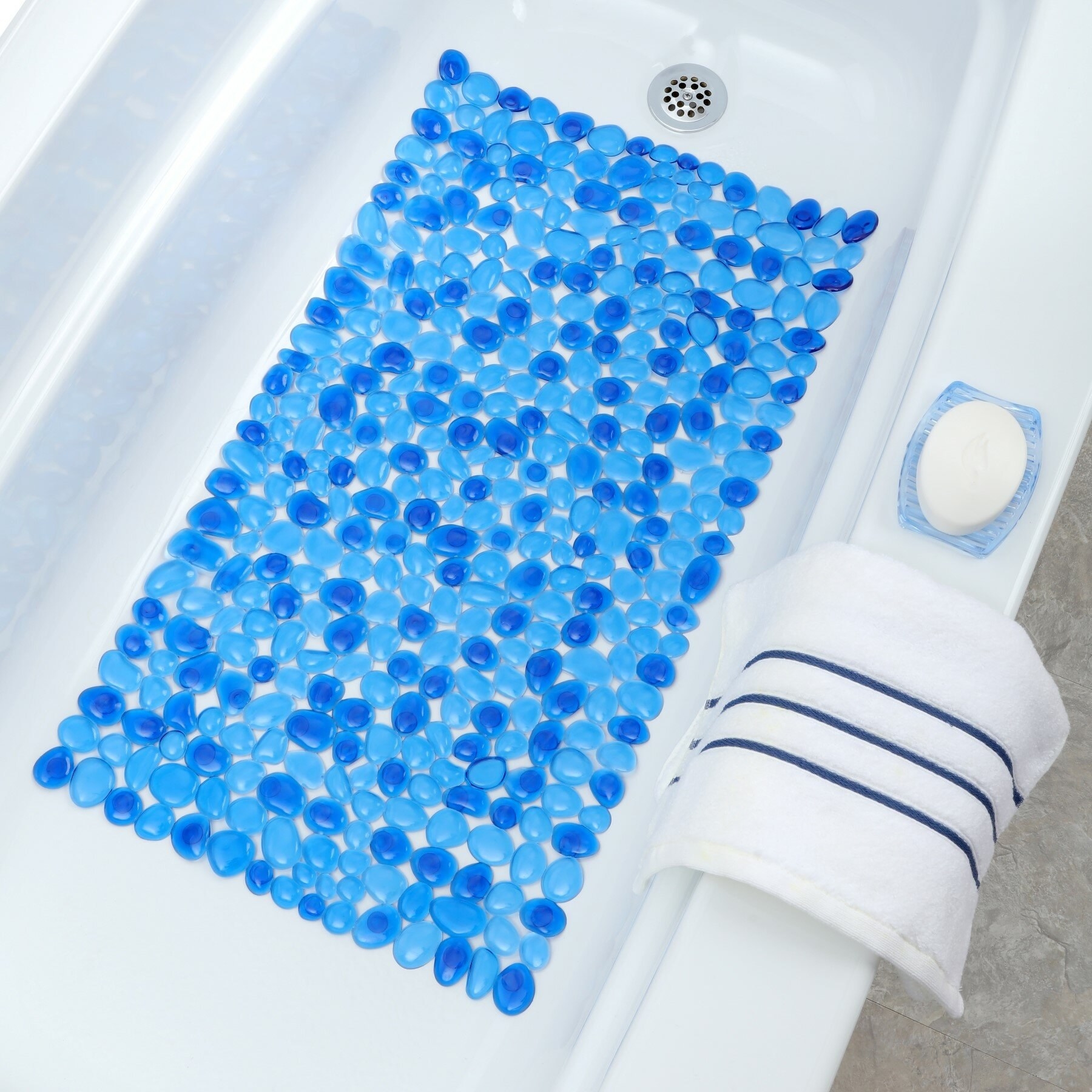 A blue pebbled bath mat in a white bath tub