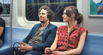 Gretta and Dan listening to music on the subway and dancing with their shoulders
