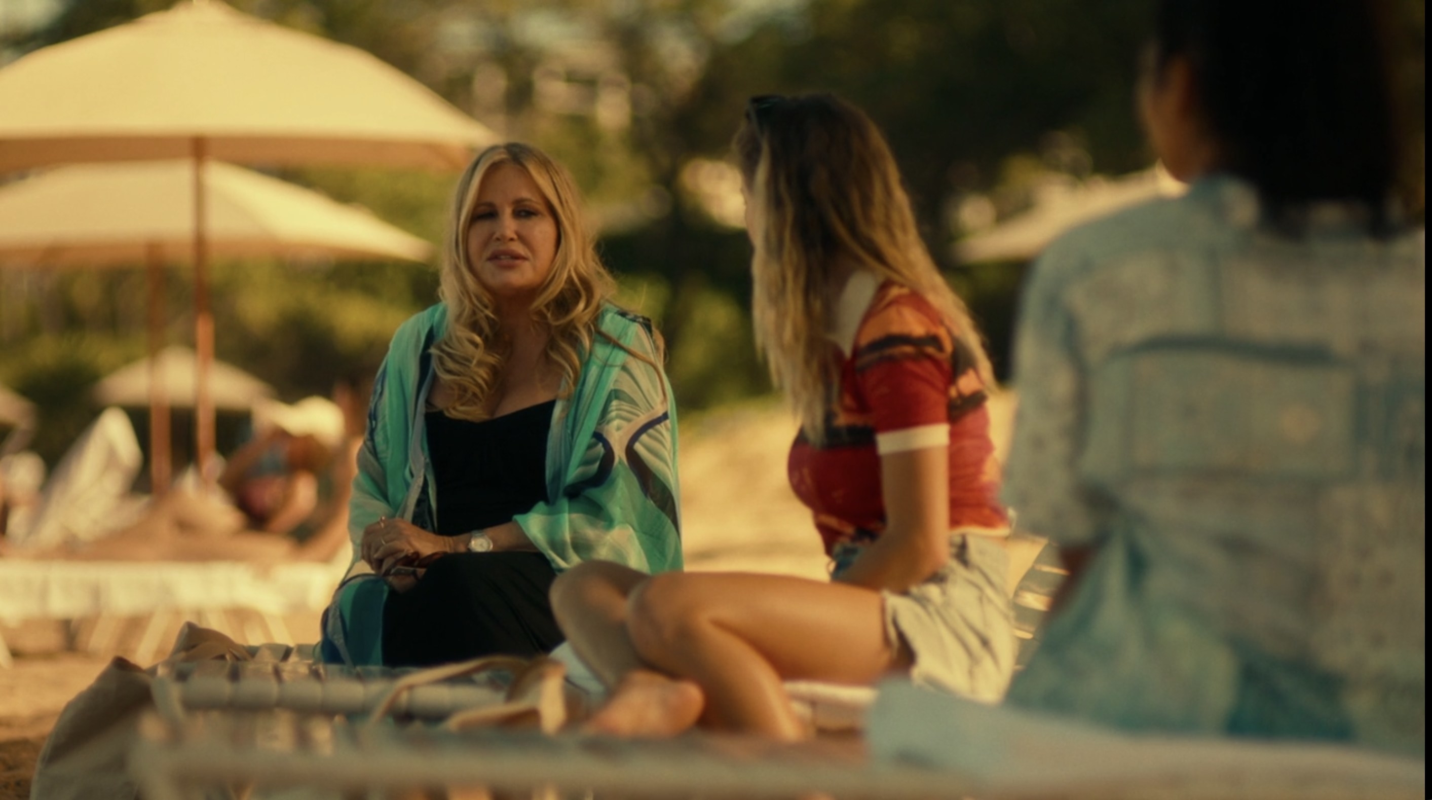 Tanya sitting on a beach lounger talking to Olivia and Paula