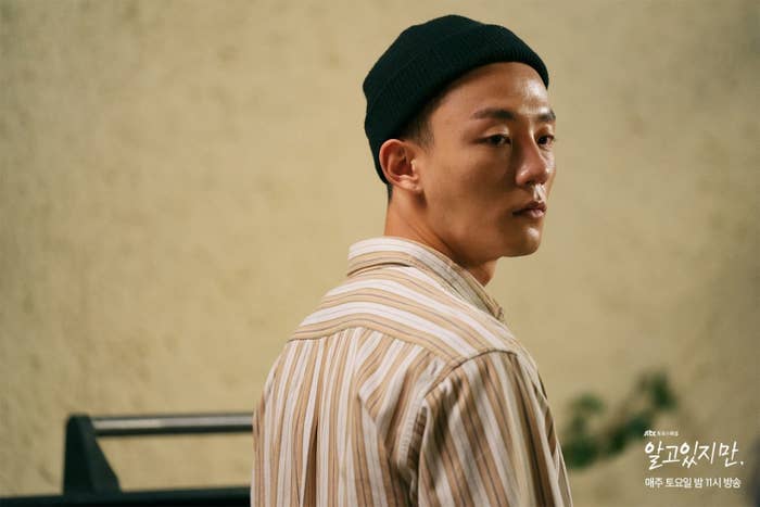 Min-gwi with a black hat and striped shirt looking away from camera