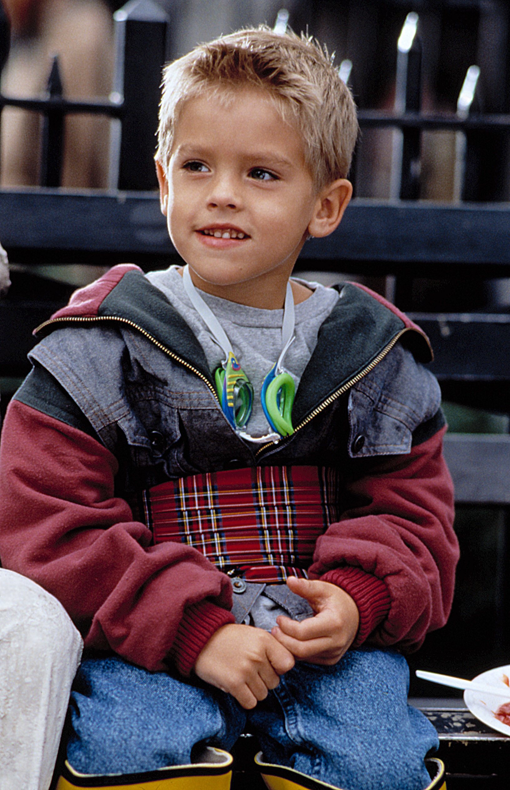A young Cole Sprouse sitting on a park bench in New York City