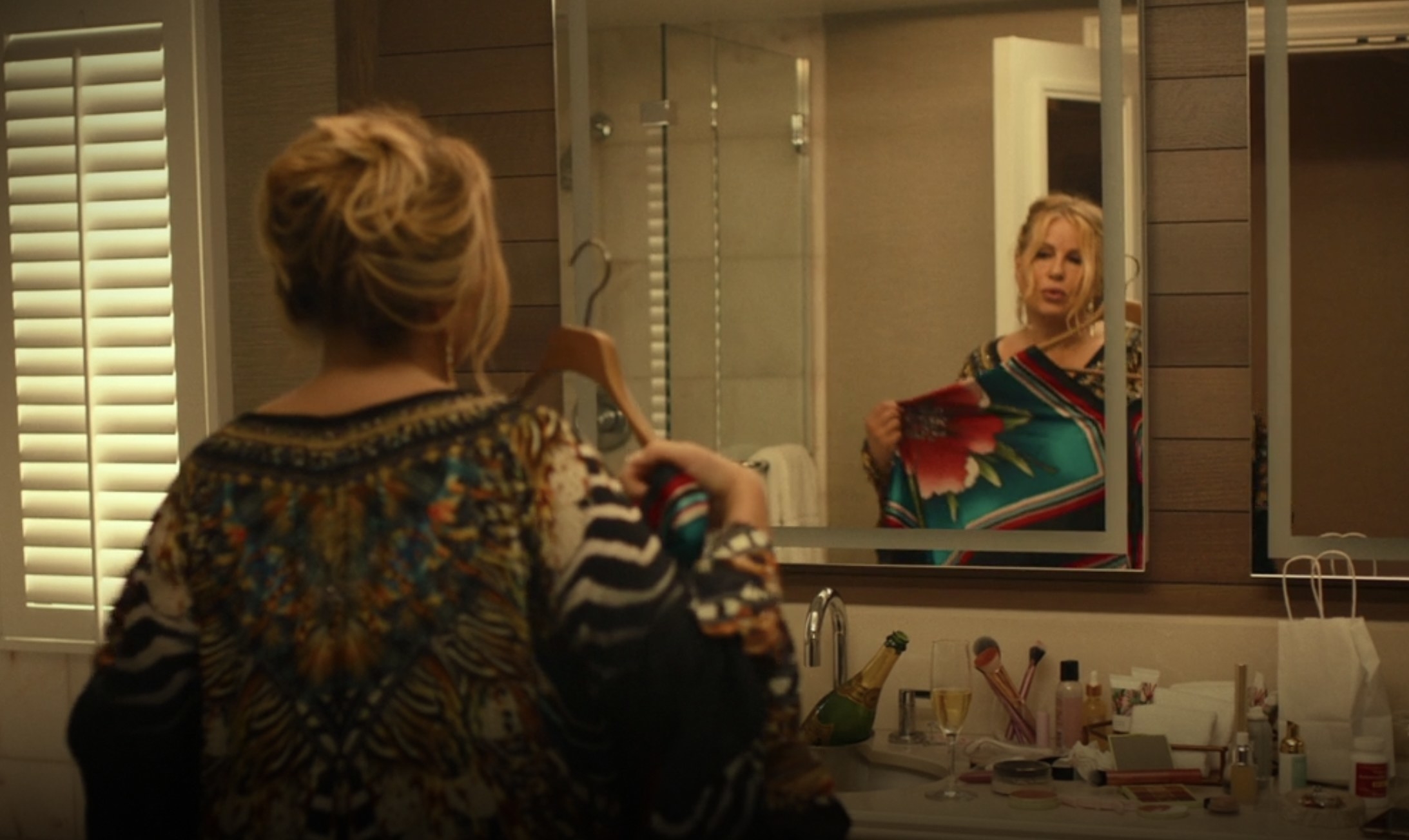 tanya holding a flower print dress up to her body in front of a mirror